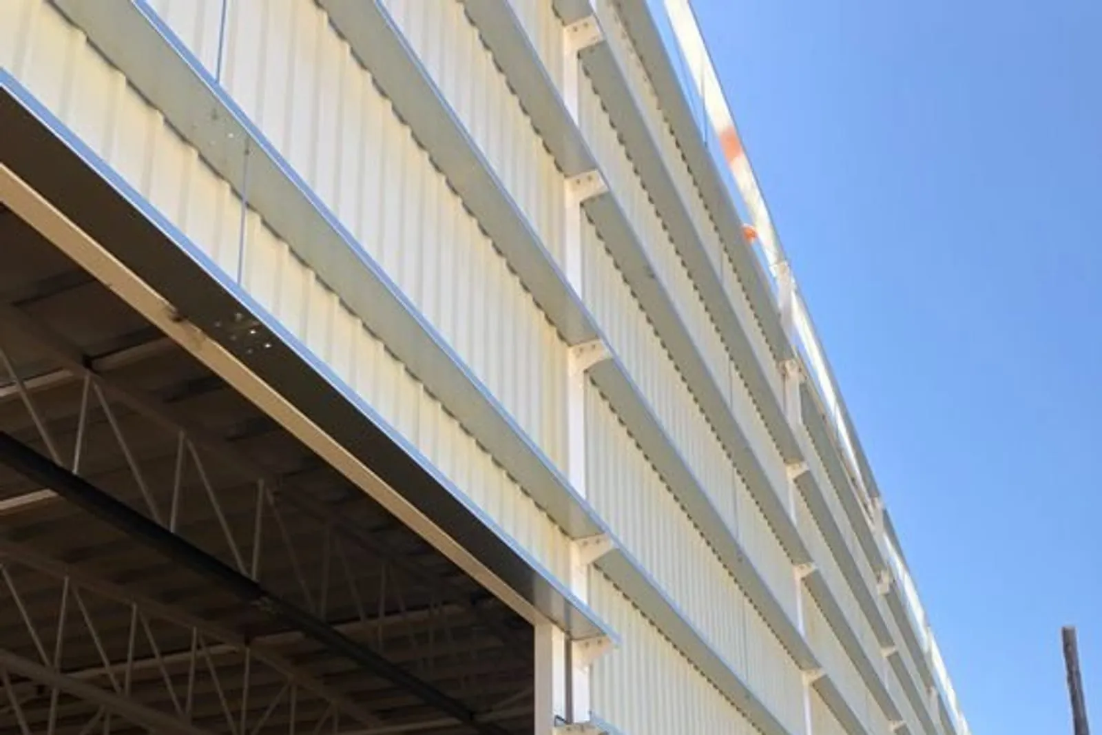 Bardage en panneaux sandwich isolants blancs posé sur la façade d'un bâtiment industriel, sous un ciel bleu
