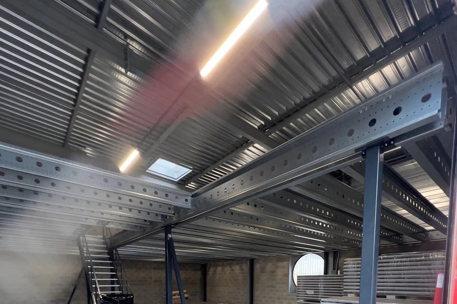Intérieur du bâtiment : charpente et mezzanine métalliques galvanisées, tube d'éclairage