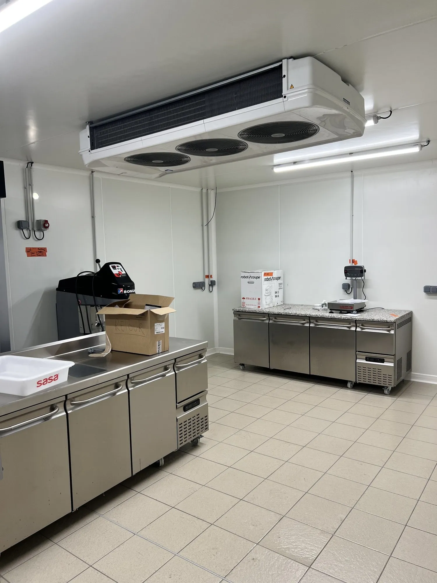 Cuisine professionnelle neuve : meubles réfrigérés en inox, évaporateur plafonnier et sol carrelé