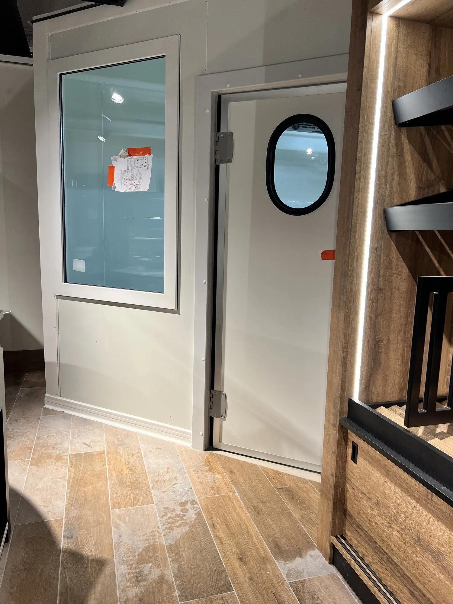Porte battante à hublot ovale entre la cuisine et la salle, à côté d'une baie vitrée