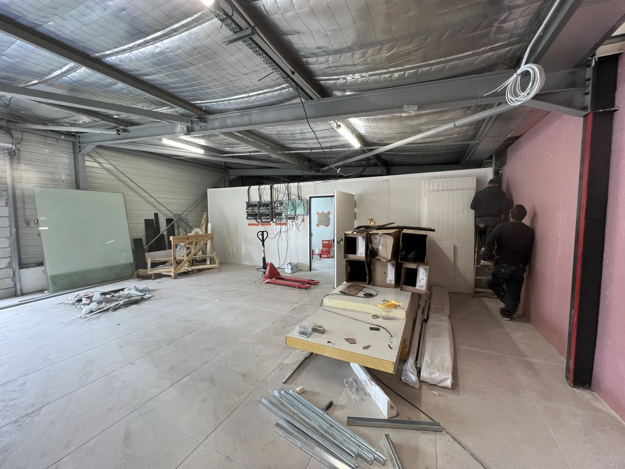 Hall industriel avec les panneaux sandwich de la chambre froide en cours d'assemblage, transpalette et outillage