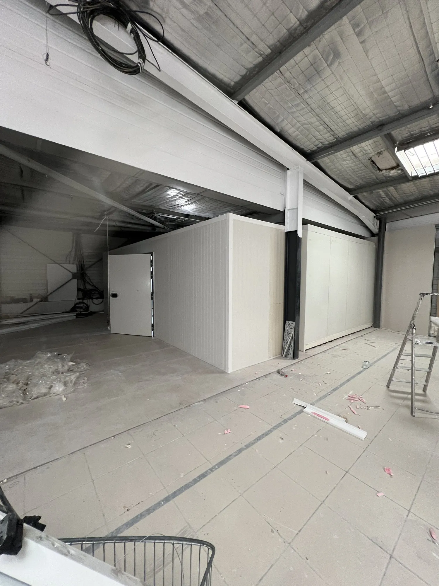 Chambre froide en panneaux blancs montée sous la mezzanine métallique d'un bâtiment industriel