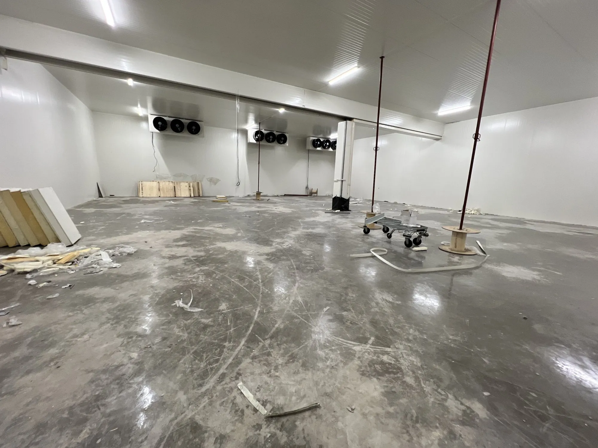 Intérieur de la grande chambre froide terminée, panneaux blancs, évaporateurs au fond et outillage au sol