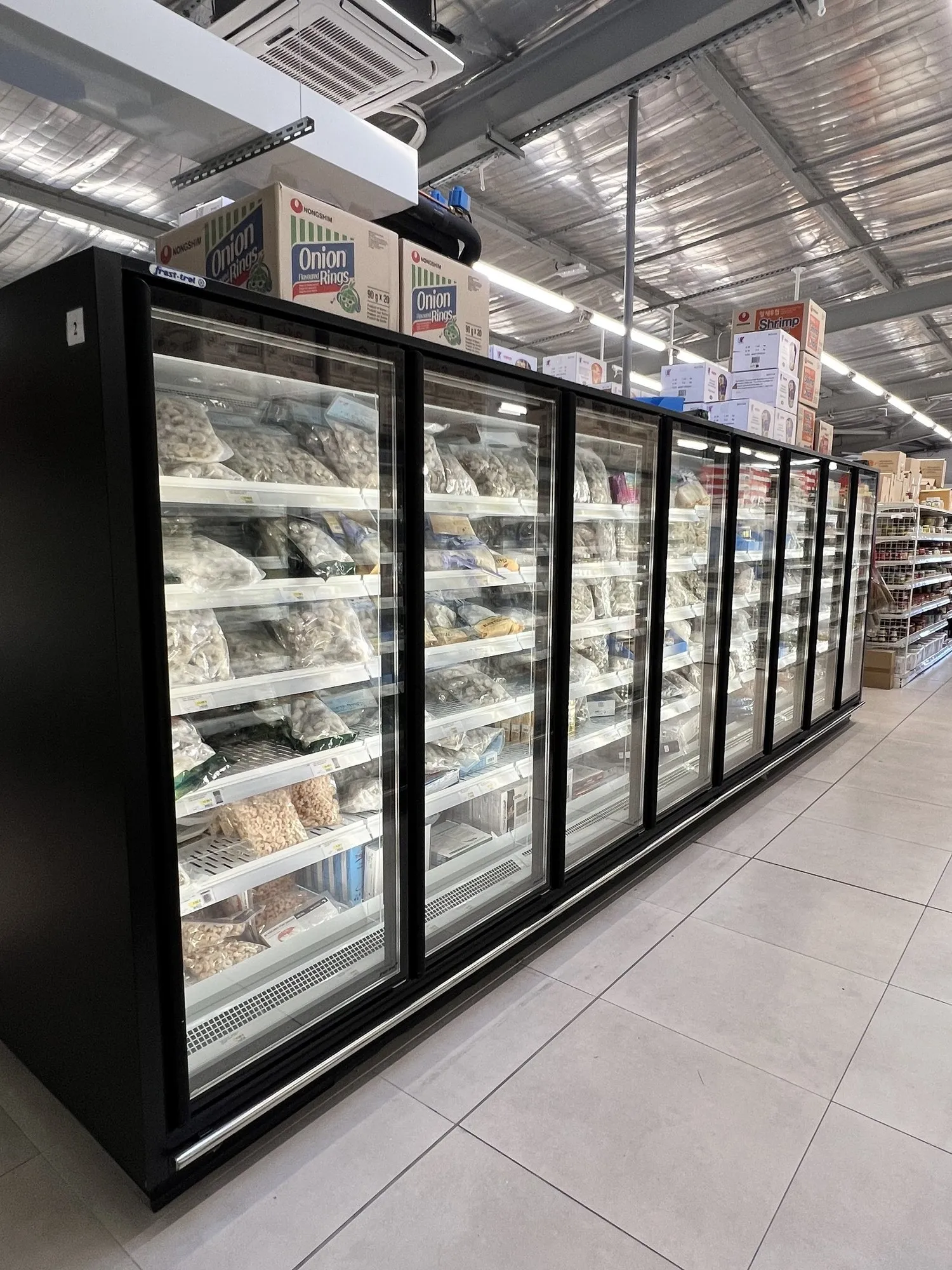 Armoires réfrigérées vitrées de produits de la mer surgelés, allée carrelée du supermarché