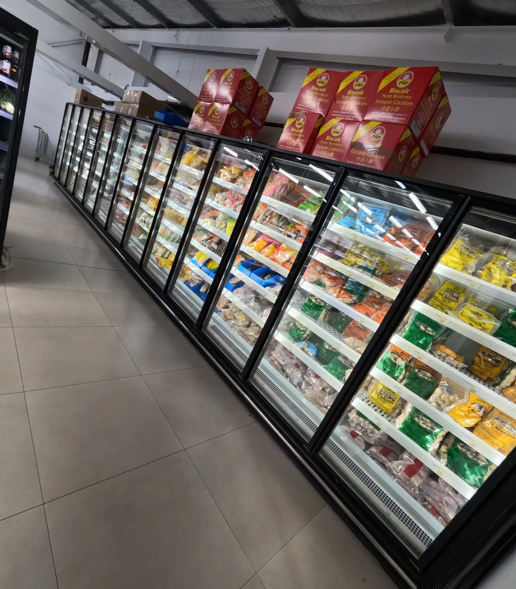 Rayon surgelés du supermarché : armoires vitrées garnies, cartons en attente sur le dessus
